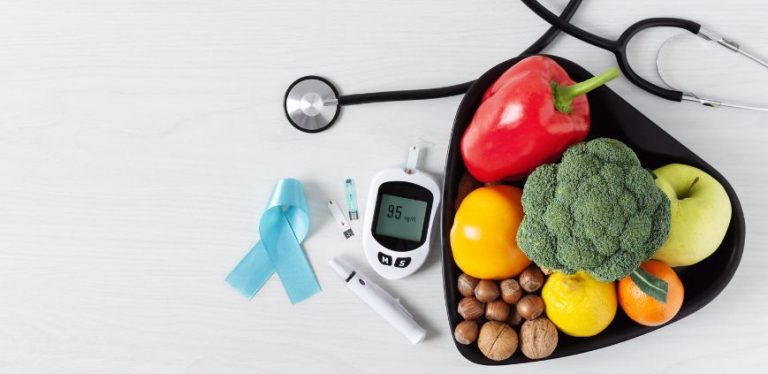 Diabetic supplies beside a bowl of fruit and vegetables