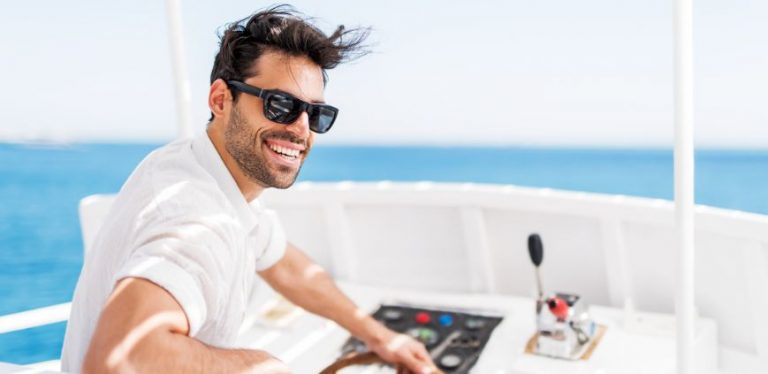 A man wearing sunglasses driving a boat.