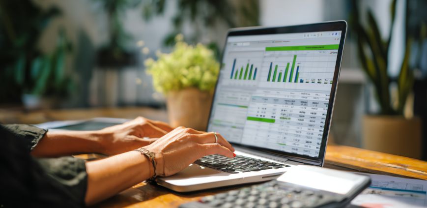 A woman using a laptop that is displaying graphs and data.